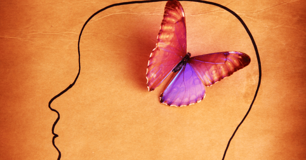 a pink butterfly rests on a human head signifying a beautiful mind